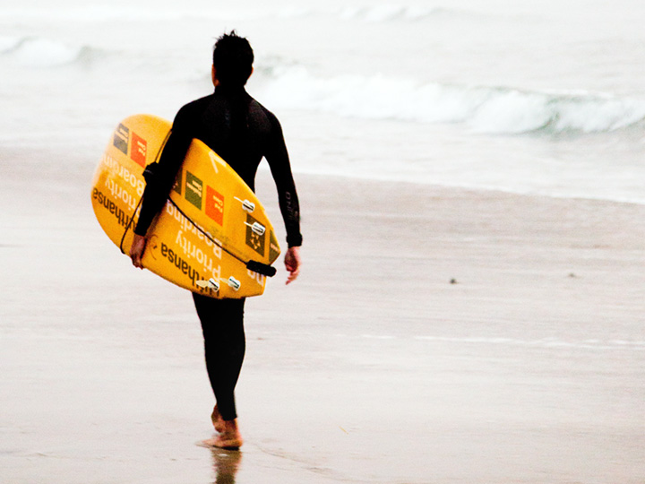 man-with-surfboard-made-from-upcycled-lufthansa-wayfinding-signage